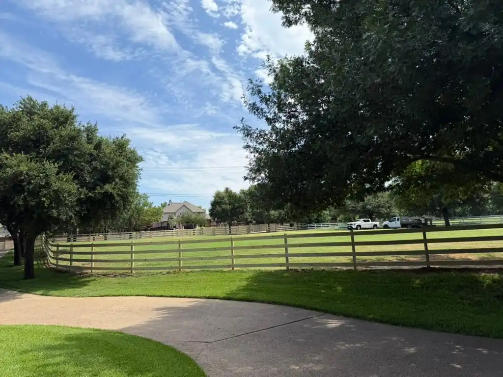 Four rail ranch fence curving around an estate lawn